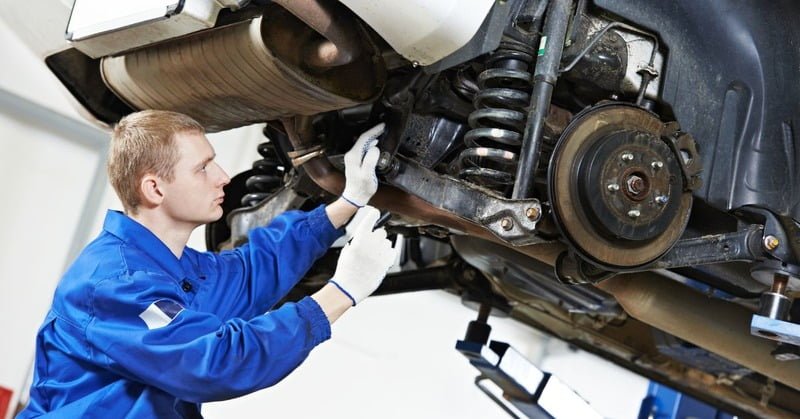 A licensed mechanic inspecting both the suspension and wheel of a car.