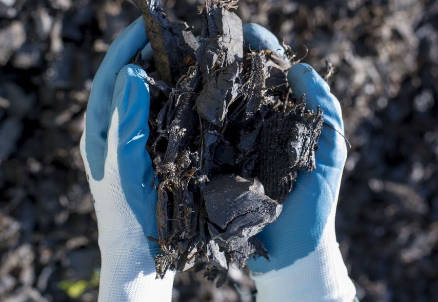 Selective focus shot of a person wearing gloves holding shredded rubber tires