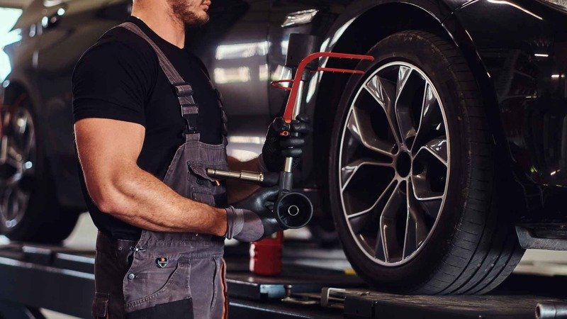 Muscular Man Is Fixing Car 039 S Wheel With Special Tool At Auto Service