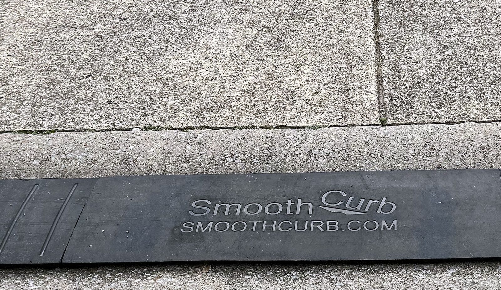 Durable Real Close-up of the real Smooth Curb ramp installed on a curb, showing the embossed logo and dense rubber texture