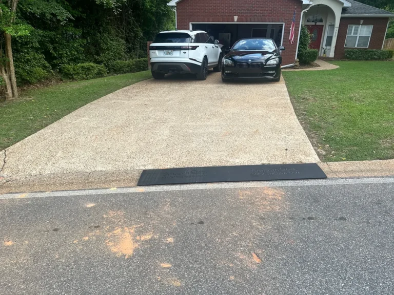 Smooth Curb rubber ramp installed at the entrance to a driveway with two parked vehicles