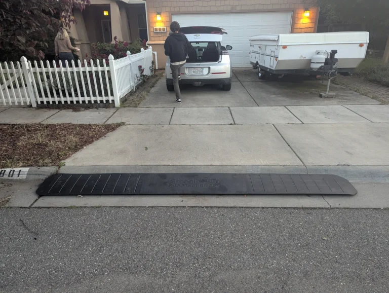 Smooth Curb ramp across a driveway entrance with a parked car and camper behind it